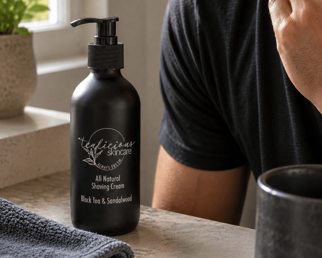 Man with a well-groomed beard touching his neck after shaving beside Tea-licious Black Tea & Sandalwood tea-infused shaving cream on a bathroom vanity in natural morning light.