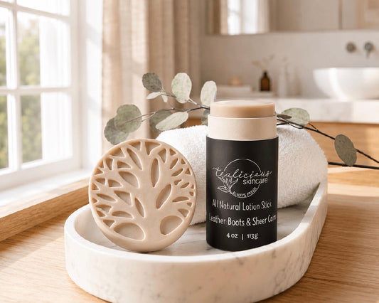 Tea-licious Skincare Leather Boots and Grit all-natural lotion stick on a marble vanity next to a rolled white towel.