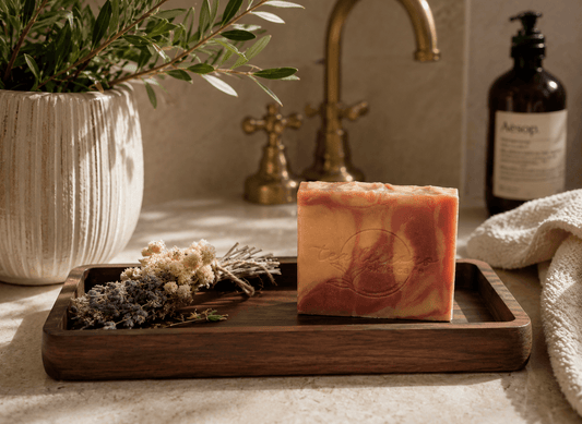 Handcrafted Moroccan Cashmere cold process soap displayed on a wooden tray in a luxury bathroom with warm natural light, brass fixtures, botanical accents, and dried flowers.