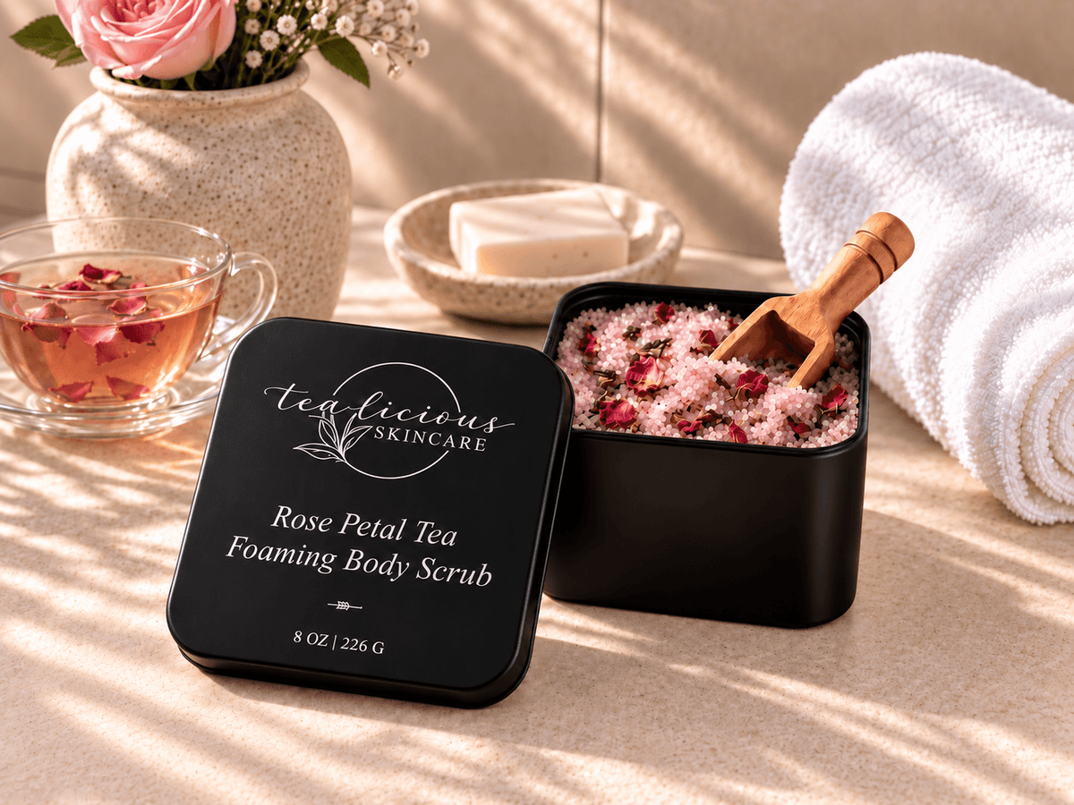 Tea-Licious Rose Petal Tea Foaming Body Scrub with pink scrub, wooden scoop, rose tea, white towel and fresh rose in warm natural light.