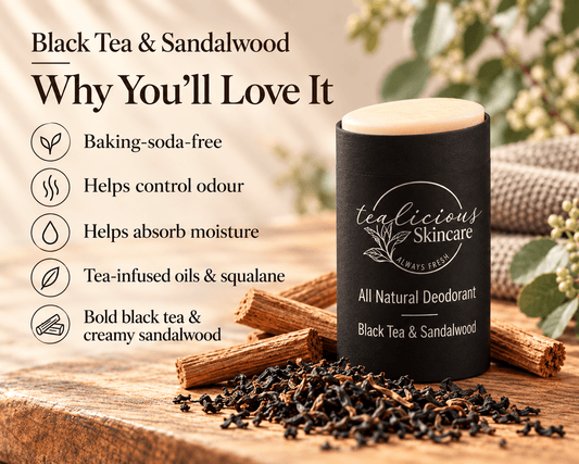 Tea-licious Black Tea & Sandalwood deodorant in a black oval container beside loose tea, sandalwood sticks and powder, with taupe towels behind.