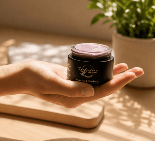 Hand holding Tea-licious White Tea Elderberry lip scrub in warm morning sunlight with soft shadows