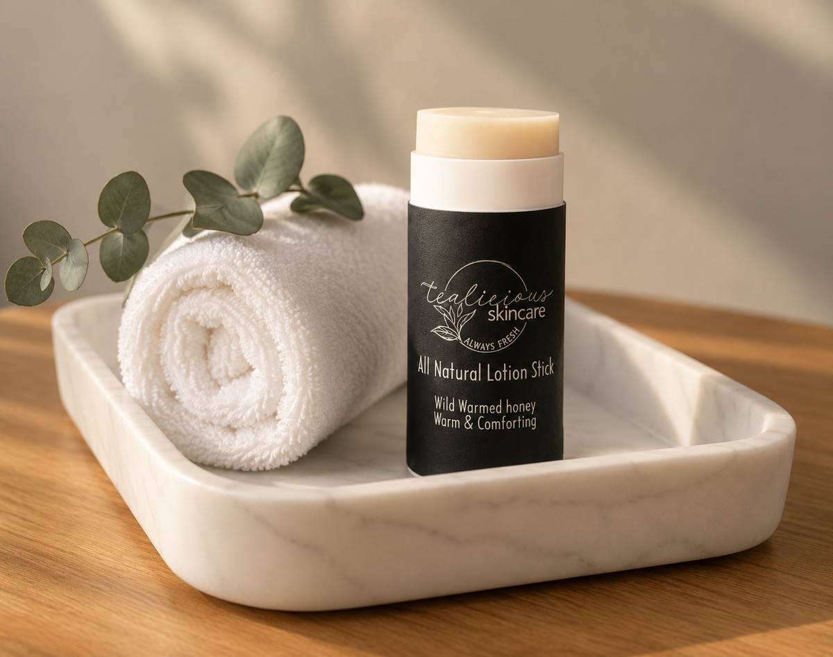 Tea-licious Skincare Wild Warmed Honey lotion stick styled on a marble tray with rolled white towel and eucalyptus, highlighting the waterless moisturizing skincare format in soft natural morning light with realistic shadows.