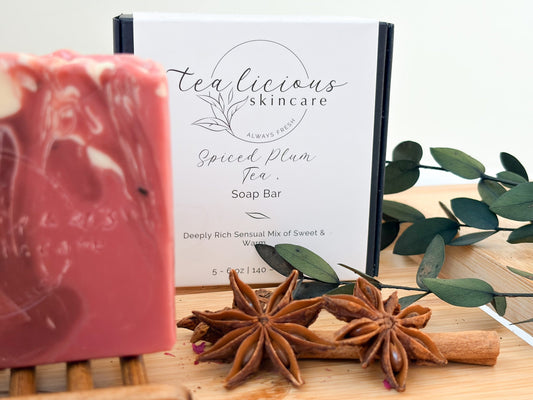 A marbled pink Spiced Plum Tea Soap Bar from Tea-licious Skincare, showcased with star anise, cinnamon sticks, and eucalyptus leaves on a wooden surface.