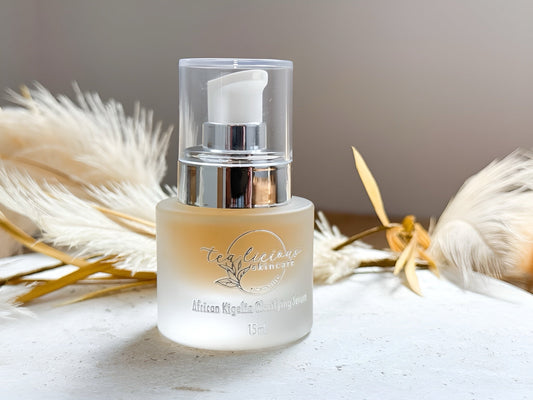 Frosted 15ml bottle of Tea-licious African Kigelia Clarifying Serum with silver pump, surrounded by soft pampas grass on a neutral background—gentle, natural skincare vibe.