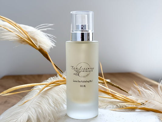 Tea infused skincare hydrating mist bottle with soft neutral botanicals on natural surface background
