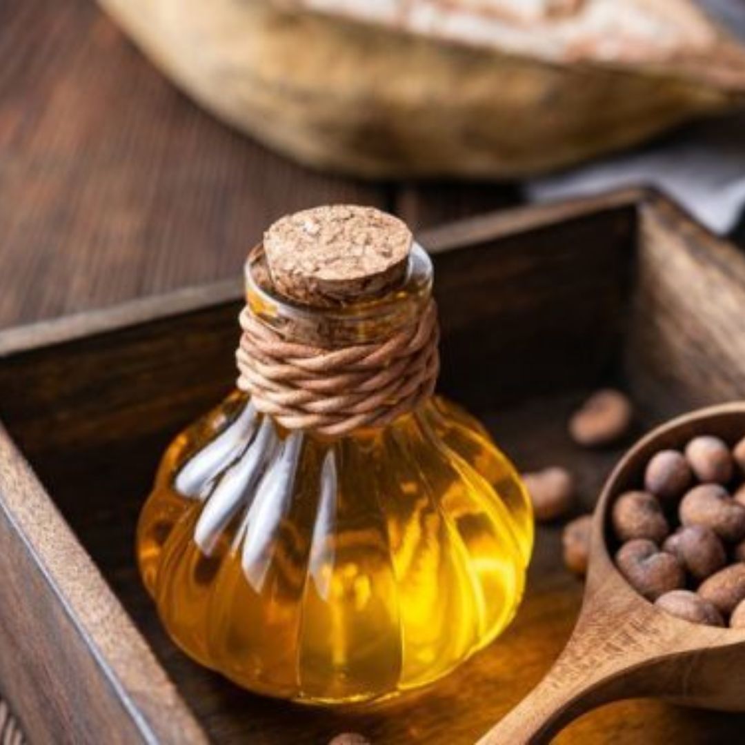 Baobab oil glass bottle with seeds on wooden tray highlighting natural skincare ingredient.