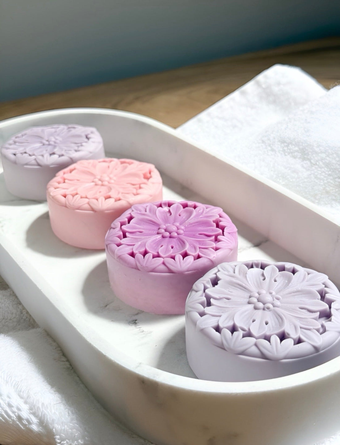 Tea-Licious solid lotion bars in floral shapes displayed on a marble tray, plastic-free moisturizer made with botanical ingredients and tea-infused skincare.