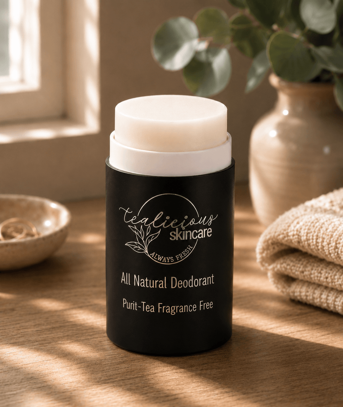 Tea-licious Skincare Fragrance Free Deodorant sitting on a counter with eucalyptus in the background 