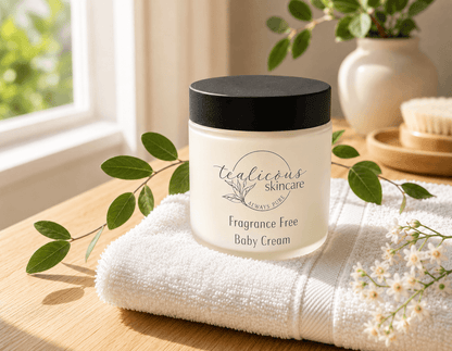 Tealicious Skincare Fragrance Free Baby Cream jar on a towel with greenery in the background