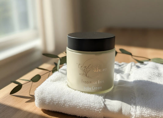 Jar of baby cream on a white towel with green leaves in the background