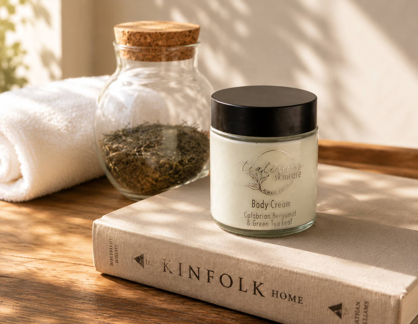 Tea-licious Calabrian Bergamot & Green Tea body cream styled with tea jar, towel, and warm light.