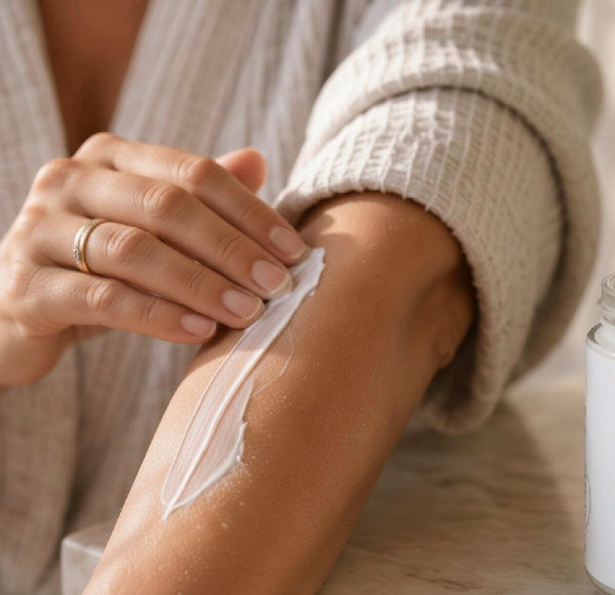 Person applying tea-licious skincare cream to their arm with a neutral background