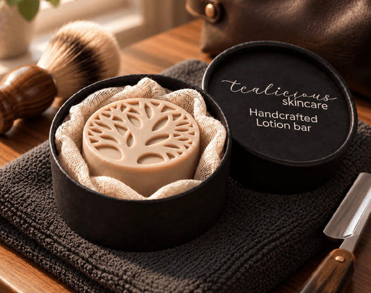 Grapefruit & Bergamot Men’s Lotion Bar in a black Tea-Licious Skincare container beside a shaving brush and razor.