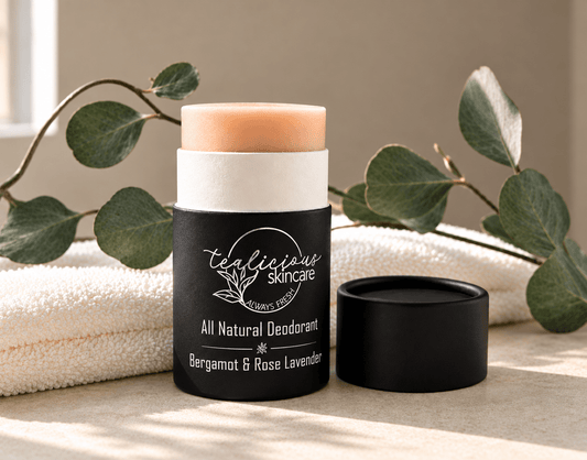 Open Tea-licious Bergamot Rose & Lavender deodorant displayed on a marble counter beside its black cap in warm sunlight.