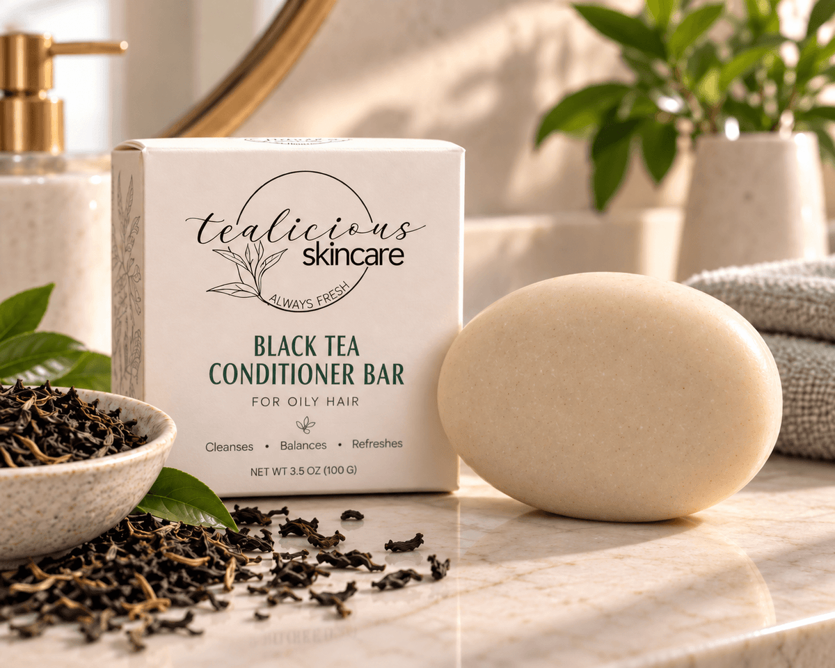 Black Tea Conditioner Bar for oily hair with Tea-Licious Skincare packaging and a subtle pink hibiscus accent on a wet shower ledge.