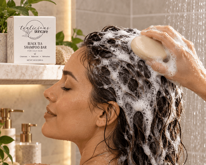 Woman using Tea-Licious Black Tea Shampoo Bar for oily hair in the shower, working the solid bar through wet hair with a rich foamy lather.