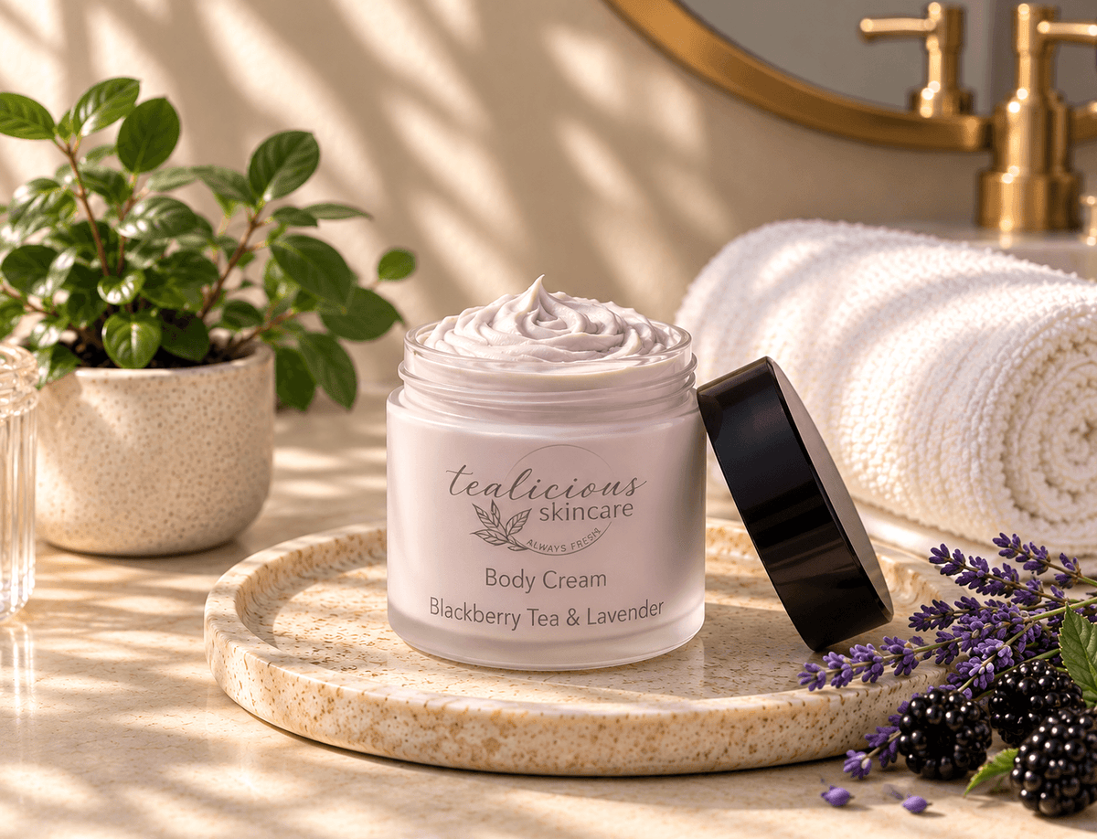 Tea-Licious Blackberry Tea & Lavender Body Cream on a stone tray with lavender, blackberries and soft towels in warm natural light.