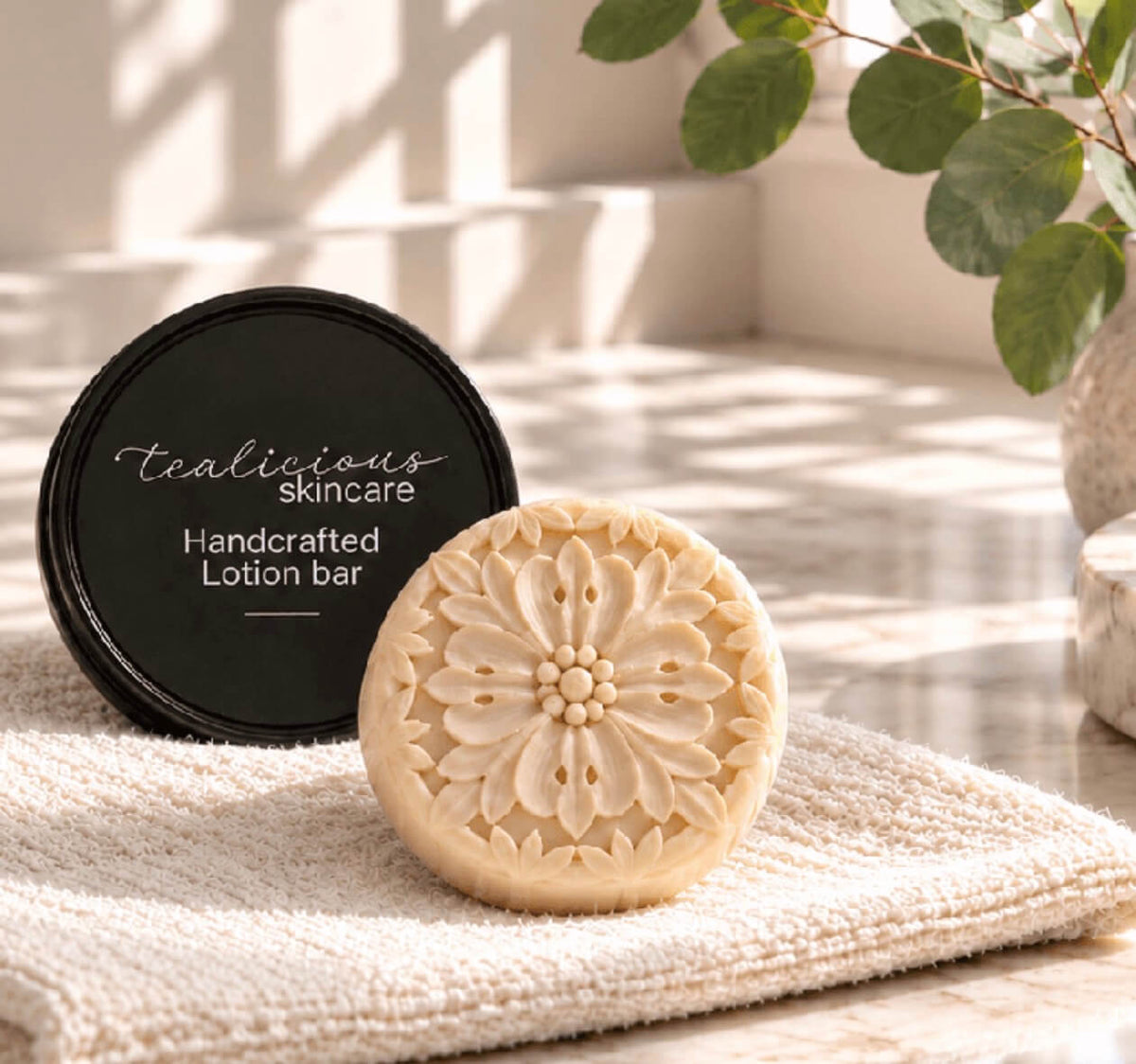 Cocoa Butter & Cashmere tea-infused lotion bar with handcrafted floral design beside its tin on a folded towel, providing concentrated waterless moisture for dry skin.