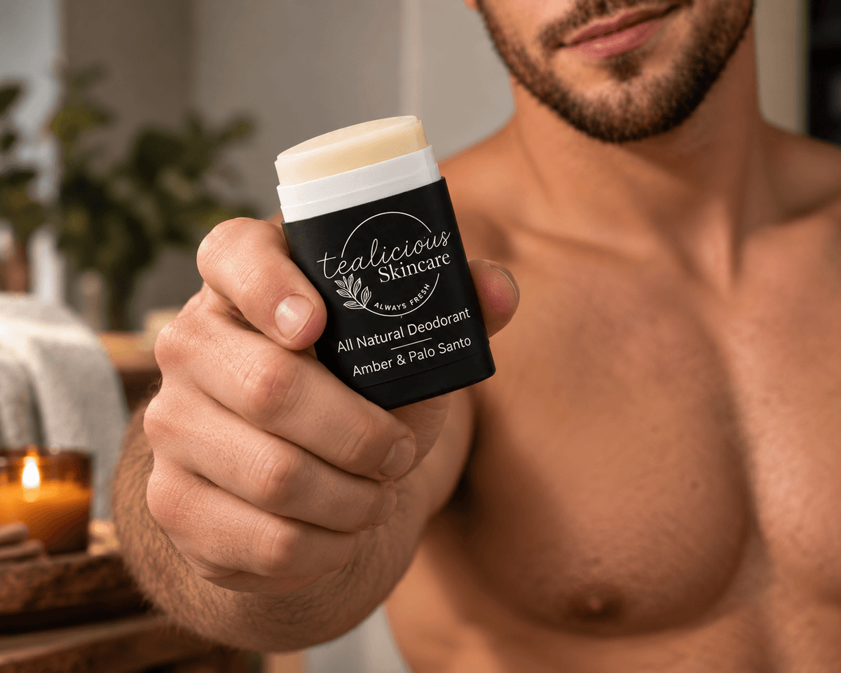Man holding Tea-Licious Amber & Palo Santo deodorant toward the camera in a warm natural setting.