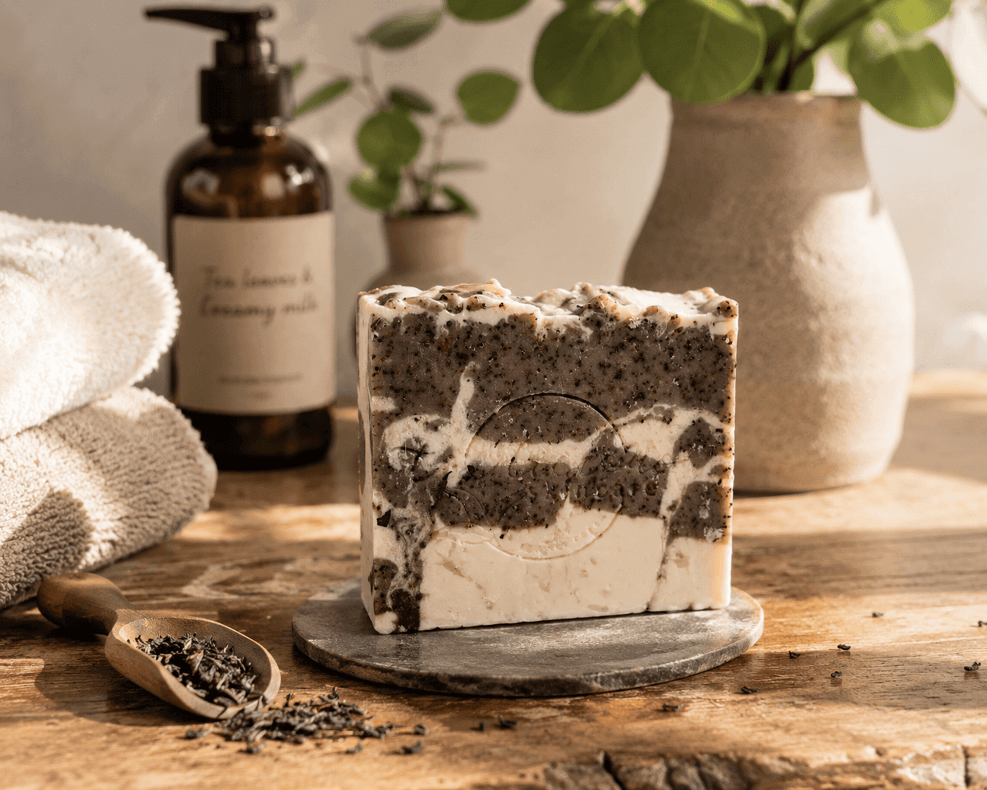 Tea-Licious Black Tea & Creamy Milk tea-infused cold process soap with real milk on a rustic wooden vanity beside loose black tea and soft towels