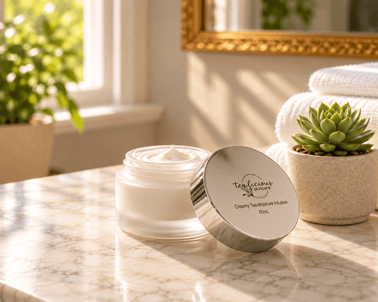 Open frosted jar of Tea-licious Guava tea Cream  Moisture Infusion with a silver lid beside a succulent and white towels.