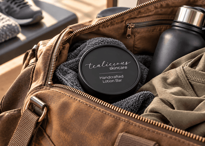 Tea-Licious handcrafted solid lotion bar in a matte black tin packed inside a brown travel bag with a towel, clothing and reusable black container