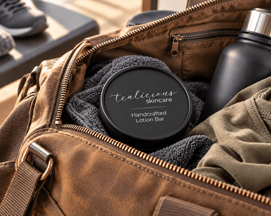 Tea-Licious handcrafted solid lotion bar in a matte black tin packed inside a brown travel bag with a towel, clothing and reusable black container