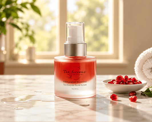Tea-licious Pomegranate Superfruit Tea Enzyme Facial Serum in a frosted pump bottle beside pomegranate seeds on a marble vanity 