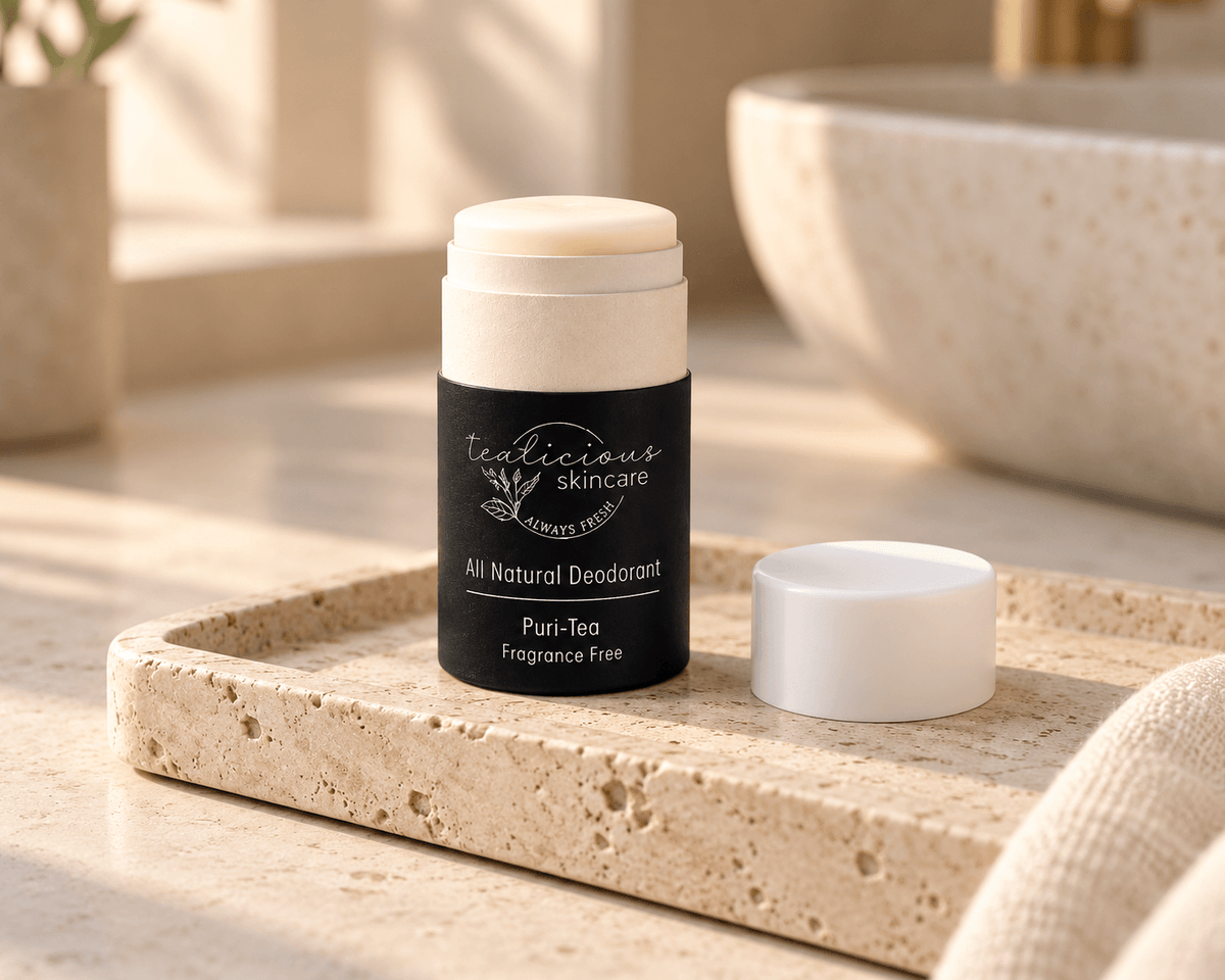 Tea-licious Puri-Tea fragrance-free deodorant with its cap beside it on a travertine tray in soft, warm bathroom light.