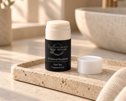 Tea-licious Puri-Tea fragrance-free deodorant with its cap beside it on a travertine tray in soft, warm bathroom light.