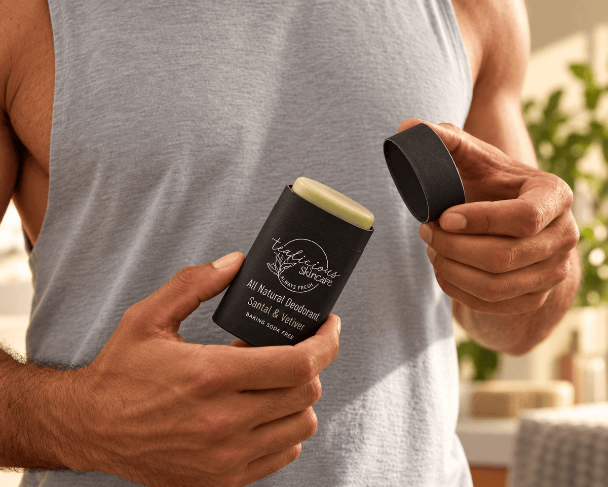 Man in a grey sleeveless shirt holding open Tea-licious Santal & Vetiver deodorant in a black oval container and its matching lid.