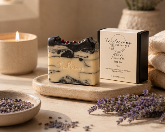 Tea-licious Black Lavender Charcoal Soap with gift box, dried lavender, and candle in warm spa lighting.