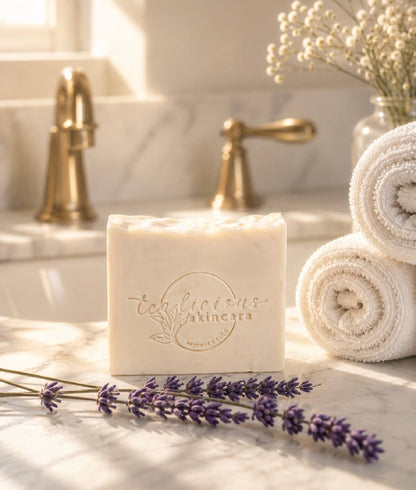 Bar of soap with 'tea-licious skincare' branding on a bathroom counter with lavender and towels.