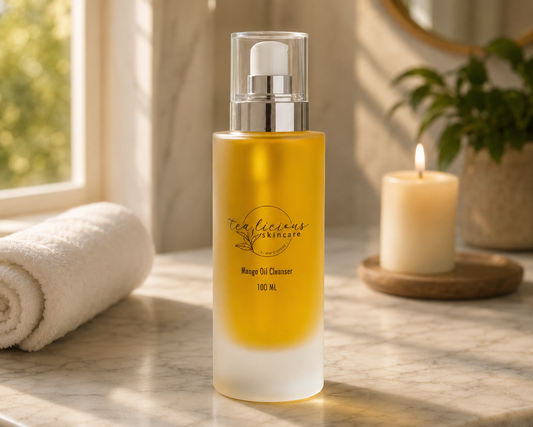 Tea-licious Mango Oil Cleanser on marble vanity with candle and towel in warm luxury bathroom