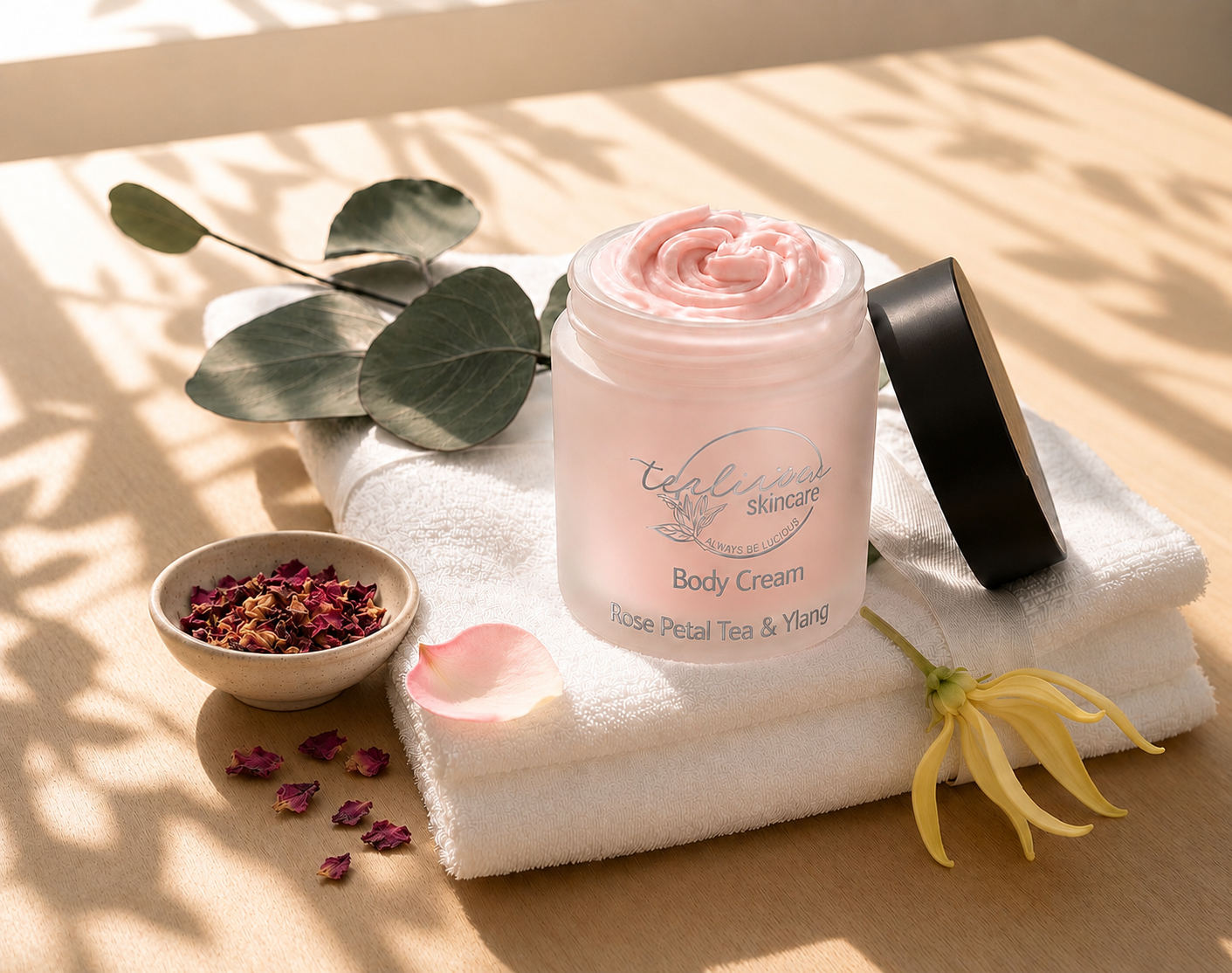 Tea-licious Rose Petal Tea & Ylang body cream with rose petals and ylang flower in soft morning light.