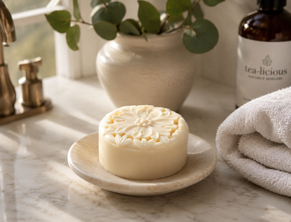 Woman applying Tea-licious tea infused lotion bar on arm in elegant sunlit bathroom with real skin texture.
