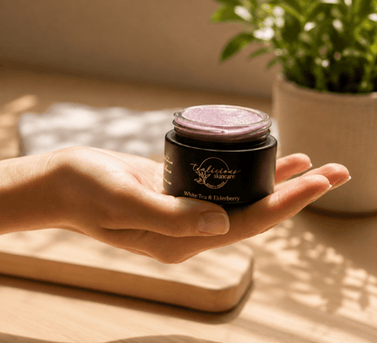 Hand holding Tea-licious White Tea Elderberry lip scrub in warm morning sunlight with soft shadows