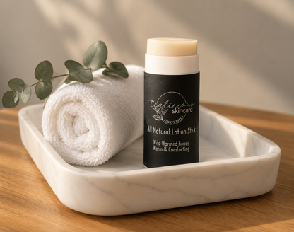 Tea-licious Skincare Wild Warmed Honey lotion stick styled on a marble tray with rolled white towel and eucalyptus, highlighting the waterless moisturizing skincare format in soft natural morning light with realistic shadows.