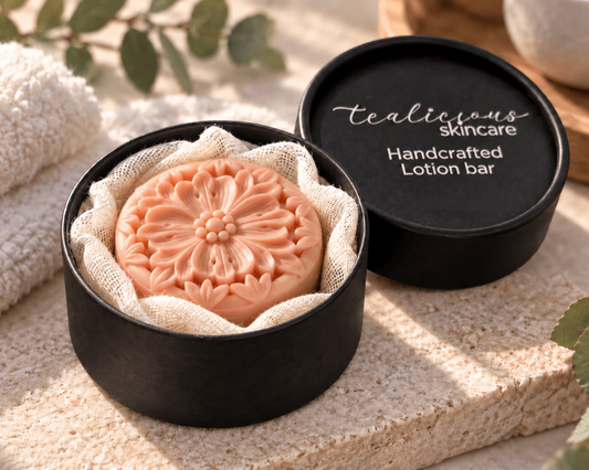 Tea-Licious Skincare floral solid lotion bar beside a black tin, for deep moisture, softer dry skin, moisture retention, a smooth non-greasy feel, and waterless travel-friendly use.