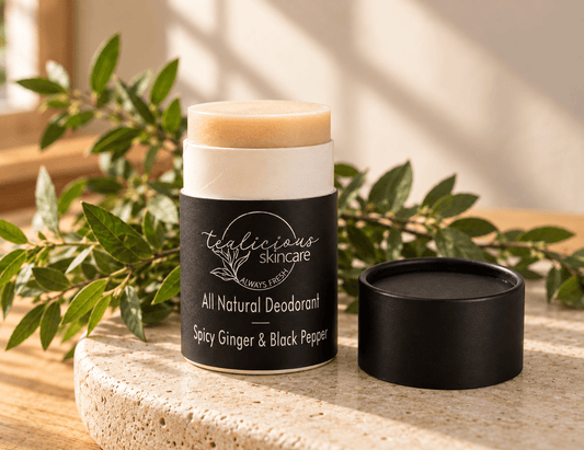 Tea-Licious Spicy Ginger & Black Pepper natural deodorant with cap beside it in warm natural sunlight and greenery.