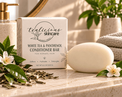 Tea-Licious White Tea & Panthenol Conditioner Bar for normal hair beside its cream box with white tea blossoms and green leaves.