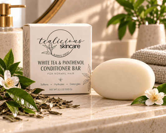 Tea-Licious White Tea & Panthenol Conditioner Bar for normal hair beside its cream box with white tea blossoms and green leaves.