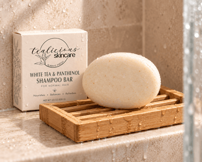 Tea-Licious White Tea & Panthenol Shampoo Bar resting on a bamboo drying rack beside its box in a wet shower setting.